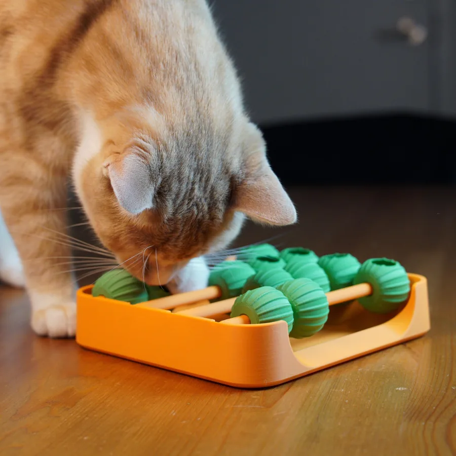 Künefe nosing at a tray of green 3D-printed balls on rods, fishing for the treats inside them